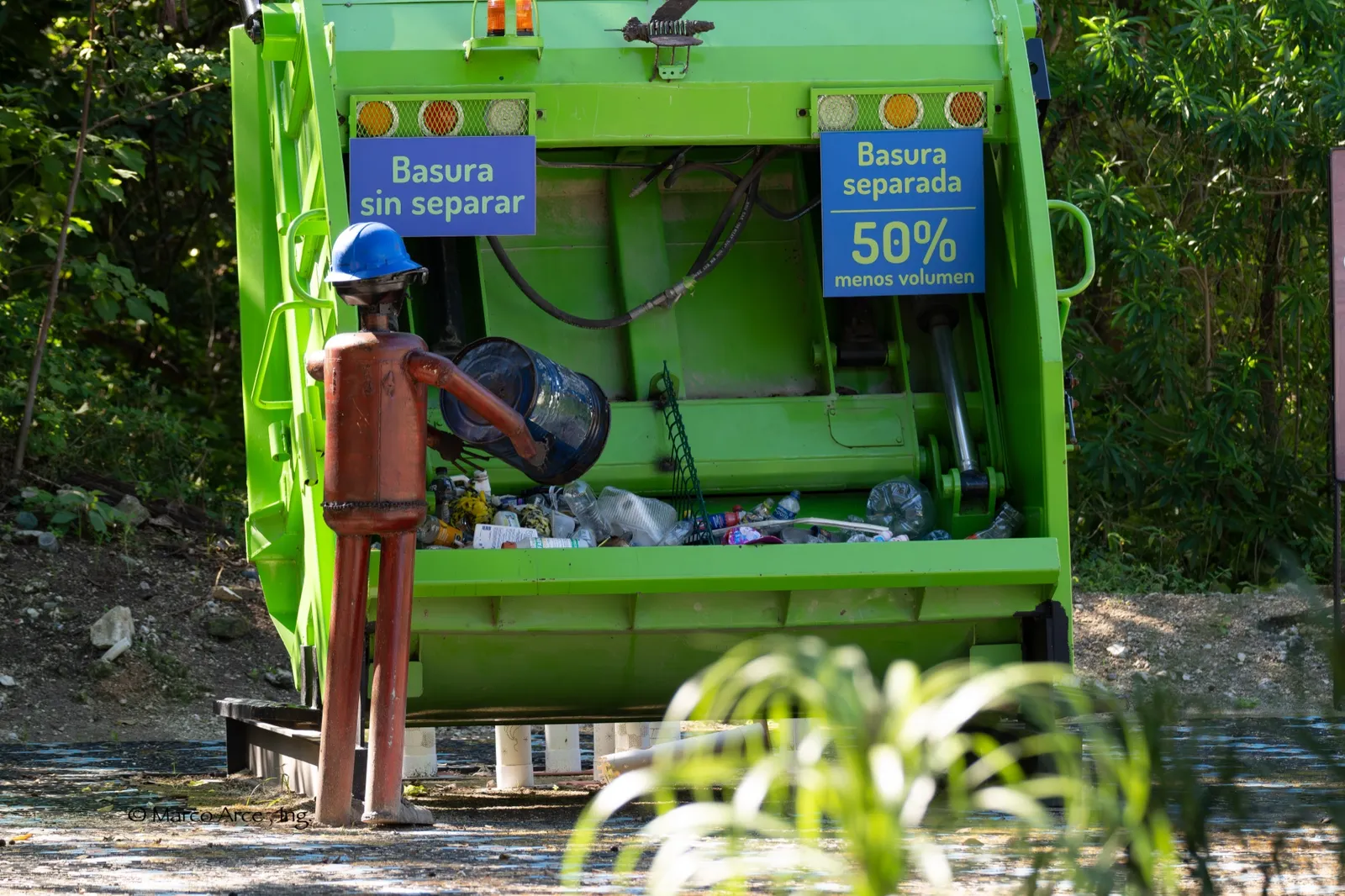 The back of a rubbish truck with signs reading ‘Basura sin separar’ and ‘Basura separada, 50% menos volumen’